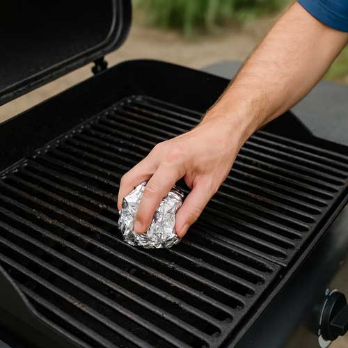 Cleaning grill grates with aluminum foil Close-up of someone cleaning grill grates with aluminum foil