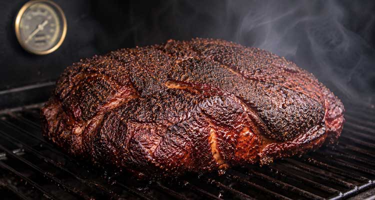 Pork shoulder smoking on smoker with bark formation