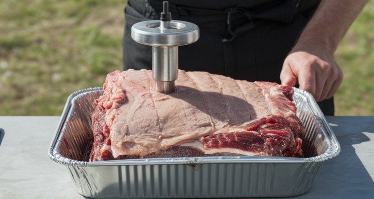 Injecting the Brisket Flat Meat injector inserted into the flat of a trimmed brisket