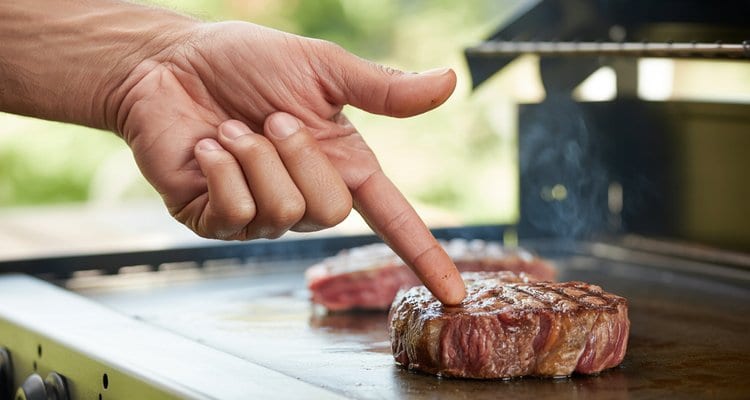 Steak Doneness Finger Test Technique Hand demonstrating finger test technique for checking steak doneness
