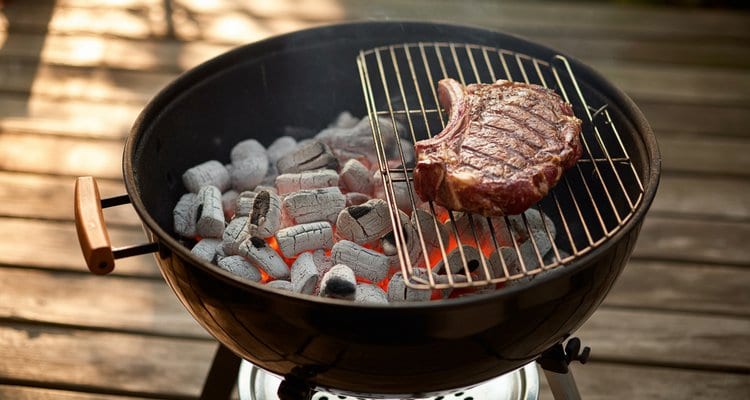 Two-Zone Charcoal Grill Setup Charcoal grill showing two-zone setup with coals banked to one side for indirect cooking