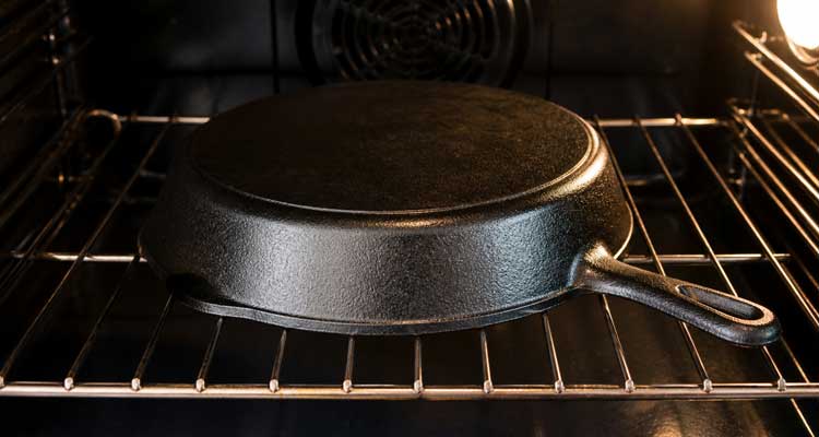 Cast iron skillet upside down on an oven rack for seasoning