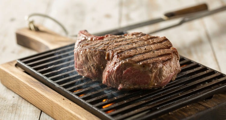 Grilling Chuck Steak — Two-Zone Setup for Searing and Indirect Finish Beef chuck steak on a hot grill grate with dark sear marks and visible sizzle