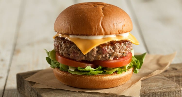 Beef and Pork Burger Recipe A juicy beef and pork burger on a toasted brioche bun with melted cheddar cheese, lettuce, and tomato on a rustic wooden surface
