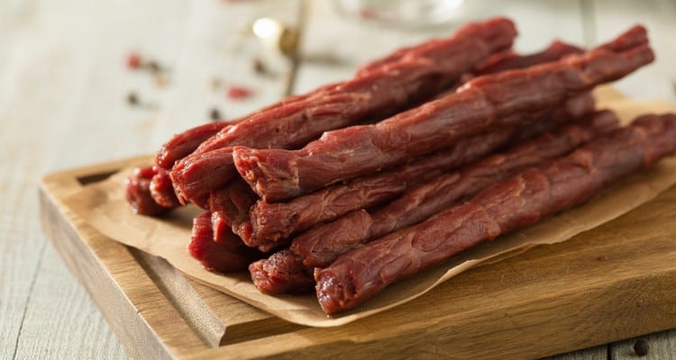 Homemade Smoked Beef Sticks Homemade smoked beef sticks on a rustic wooden cutting board